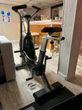 The LCD console interface of an Assault Fitness Elite Air Bike displaying the 20/10 custom interval training program selection screen.