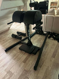 An athlete performing a glute-ham raise on a Rogue Abram GHD 2.0 inside a commercial training facility.