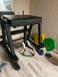 An athlete performing a posterior chain reverse hyperextension exercise on a Rogue Z Hyper machine in a training facility.