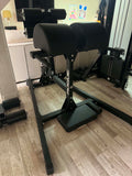 Profile view of a black Rogue Abram GHD 2.0 machine showing its triangular steel base, split hip pads, and adjustable foot roller assembly
