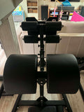 Close-up of the 10-slot adjustable swing-arm roller assembly and foam ankle pads on a Rogue Abram GHD 2.0.